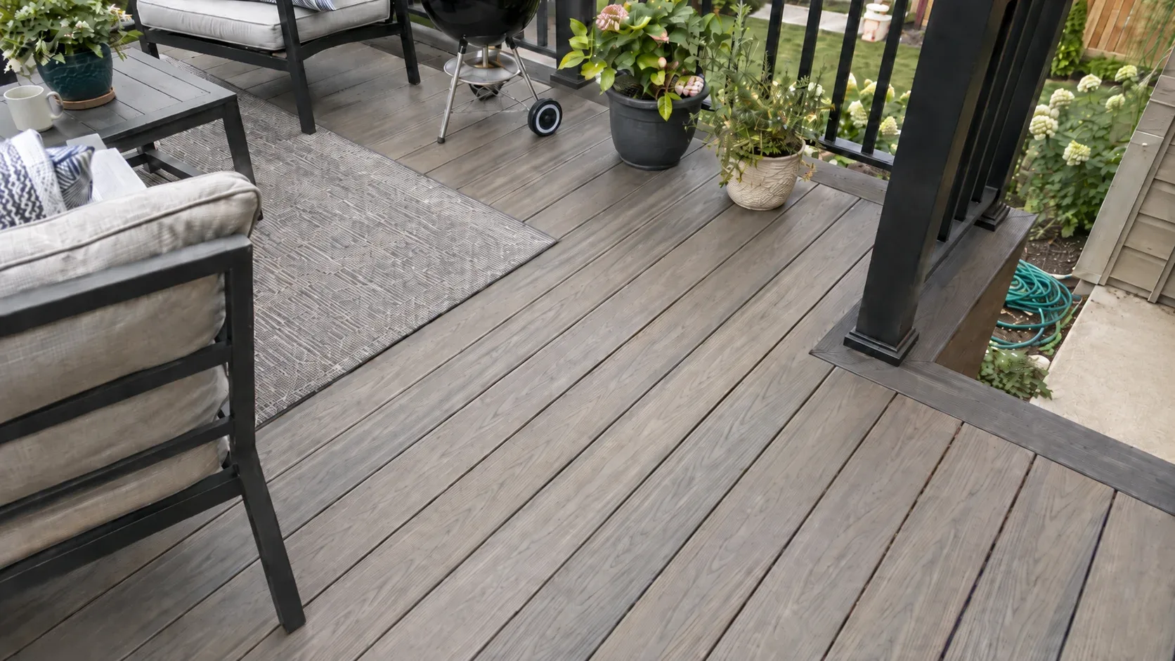 A close view of capped composite, embossed grain, a contrasting border board and an aluminium post foot, with no fasteners showing in the field